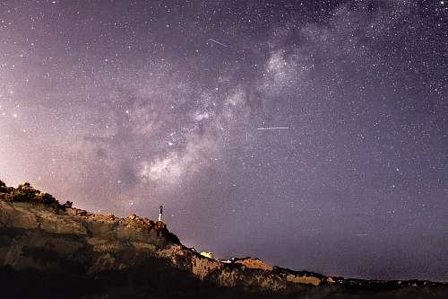 night person standing on rock formation under starry sky astronomy